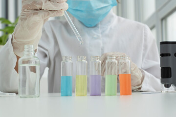 Close up image of five test tubes filled with liquids of different colors, boy's hand in protective glove is ready to put drop of solutioninto it, chemical experiments at home