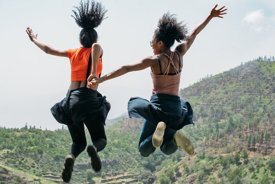 group of ethnic friends jumping on top of a mountain in cape verde