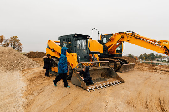 Kids climbing on a digger at construction site. 