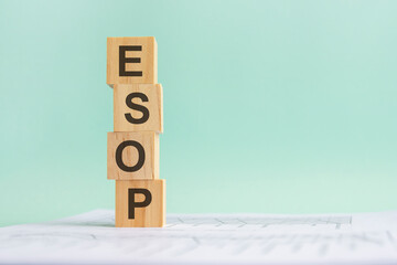 word ESOP with wood building blocks, light gray background. document with numbers on background,...