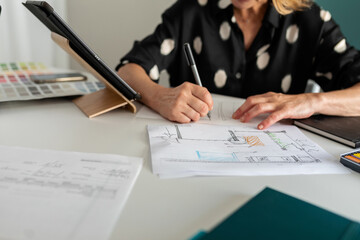 Detail of female architect correcting plans at office