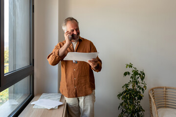 Senior man talking by phone at office