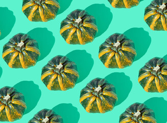 Creative optimistic Halloween pattern made of authentic green and yellow pumpkin on a pastel mint green background. Flat lay design.