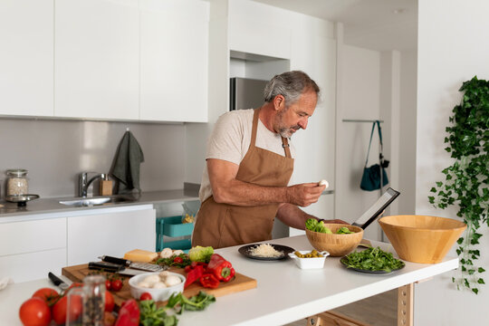 Senior man preparing lunch at kitchen