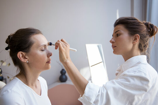 Makeup artist working with female client in studio