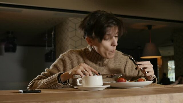 a lonely woman in a beige sweater eats salad sitting at the bar in a restaurant. High quality FullHD footage