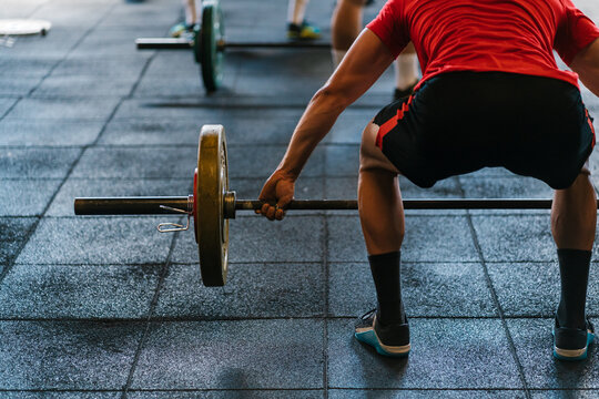 Man lifting a barbell from the ground