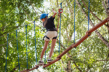 Girl (children) in the park walk along the suspension bridge. Rock climbers.