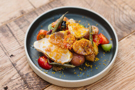 Plate of fresh nicoise salad on a rustic wooden table.