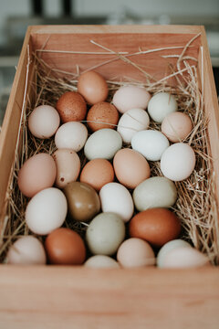 Colourful eggs from heirloom chickens in a small wooden crate.