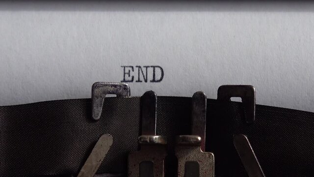 Typing word End on retro typewriter. Close up.