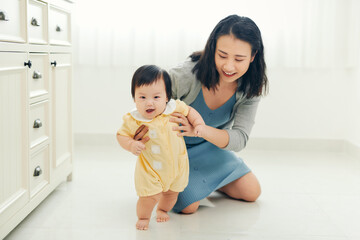 Baby taking first steps with mother's help at home