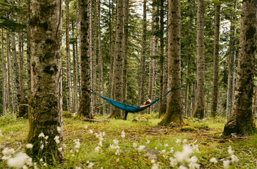 Woman relaxing in a hammock in a green forest