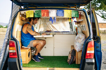 Young man using laptop in camper van