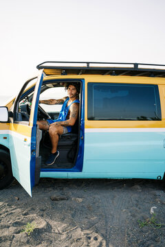 Adventurer sitting in camper van on beach