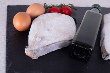 Catfish fillet steak on the table on a slate board. Ingredients for cooking fish. Plmidor, eggs, salt, fresh raw fish