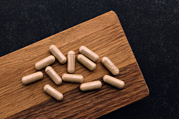 lion's mane supplement capsules on wooden board and on chalkboard background. immune prevention care concept