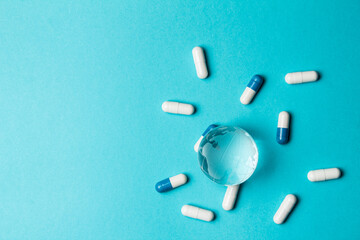Global epidemic. Glass globe Earth and capsule pill white-blue on a turquoise background. Top view.