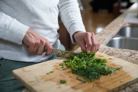 Man's hands chopping greens
