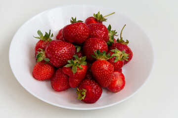 Fresh ripe strawberries in a white plate. Dessert. Close-up.