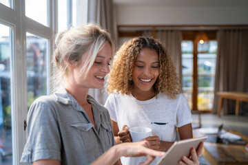 Two Women Smiling at Tablet Screen in Bright Room