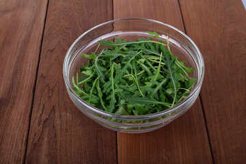 arugula salad in a plate on a wooden table. Green arugula