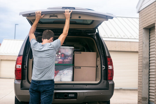Storage: Man Opens Back Of SUV To Get Box