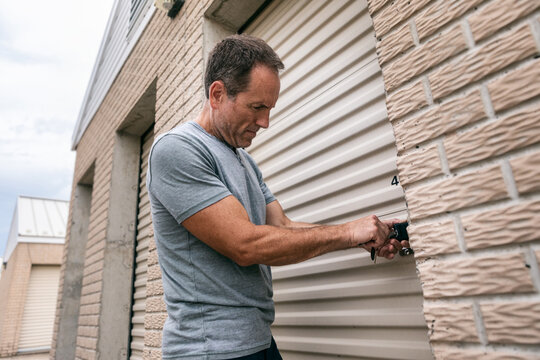 Storage: Man Unlocking Padlock On Unit