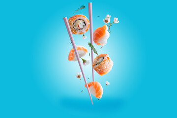 The concept of flying sushi. Rolls and sushi with salmon levitation with flowers and chopsticks on...