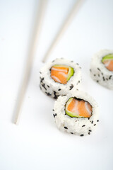 California sushi roll with salmon and avocado on a white background with chopsticks