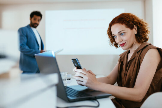 Woman using laptop and smartphone during teamwork in office
