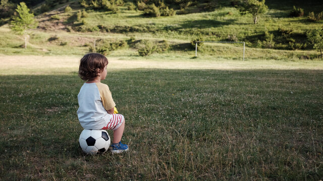 A little boy sits on his ball