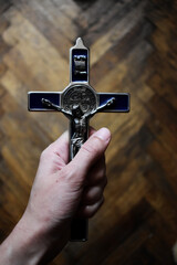 Krzyżyk z medalikiem św. Benedykta zaciśnięty w dłoni - obrazy, fototapety, plakaty