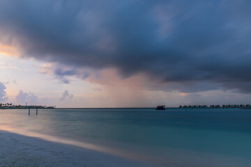 Sunset light shining on ocean waves. Maldives beach. July 2021