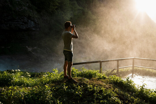 Photographer taking pictures of a waterfall on mountain