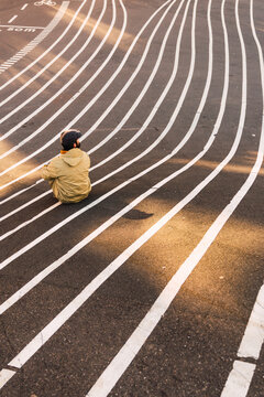 Back view of man sitting in asphalt 