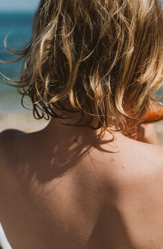 A back of a boy eating a melone by the sea
