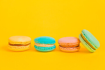 Sweet almond colorful unicorn pink blue yellow green macaron or macaroon dessert cake isolated on trendy yellow modern fashion background. French sweet cookie. Minimal food bakery concept Copy space