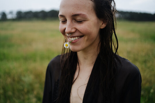 Happy woman with chamomile standing in the field