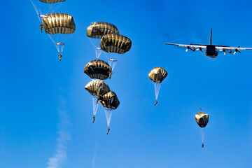 Military parachutist paratroopers parachute jumping out of a air force planes on a clear blue sky...