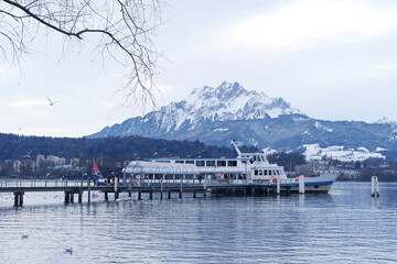 lake lucerne in switzerland, tourist white boat stands on the pier against the background of snow-capped mountains, the concept of winter entertainment for tourists