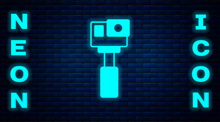 Glowing neon Action extreme camera icon isolated on brick wall background. Video camera equipment for filming extreme sports. Vector