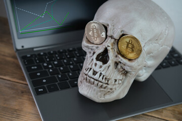 human skull on a laptop keyboard, metal bitcoins in the eye sockets, the concept of cryptocurrency mining, the transience of life, the inevitability of death, the risk of monetary transactions