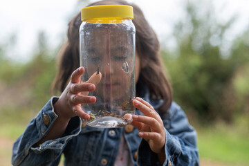 little girl holding a jar with butterflies in