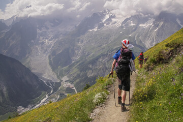 Fototapeta na wymiar Tourists walking in the mountains, Alps rucksack, cloudy weather, trekking, Tour du mont Blanc