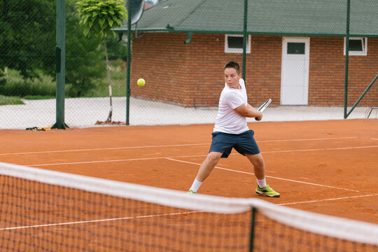 Young tennis player on the outdoor court. 