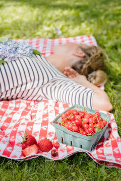 Woman Lounging on Picnic Blanket next to Summer Fruits