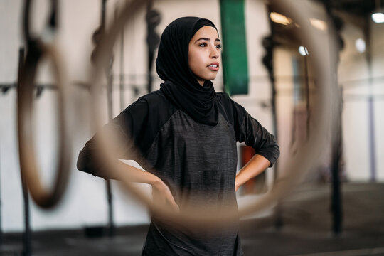Confident Muslim sportswoman standing in modern gym during workout