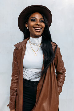 Smiling black woman in leather coat and hat
