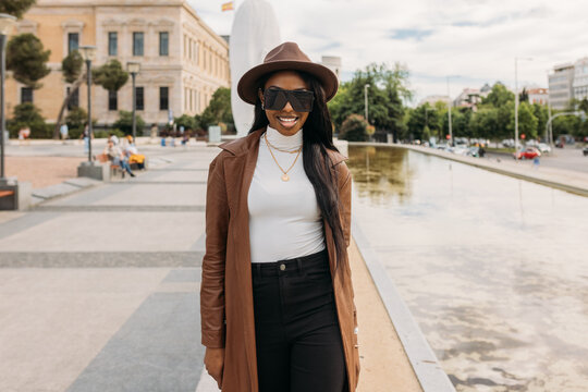 Smiling black woman in leather coat and hat